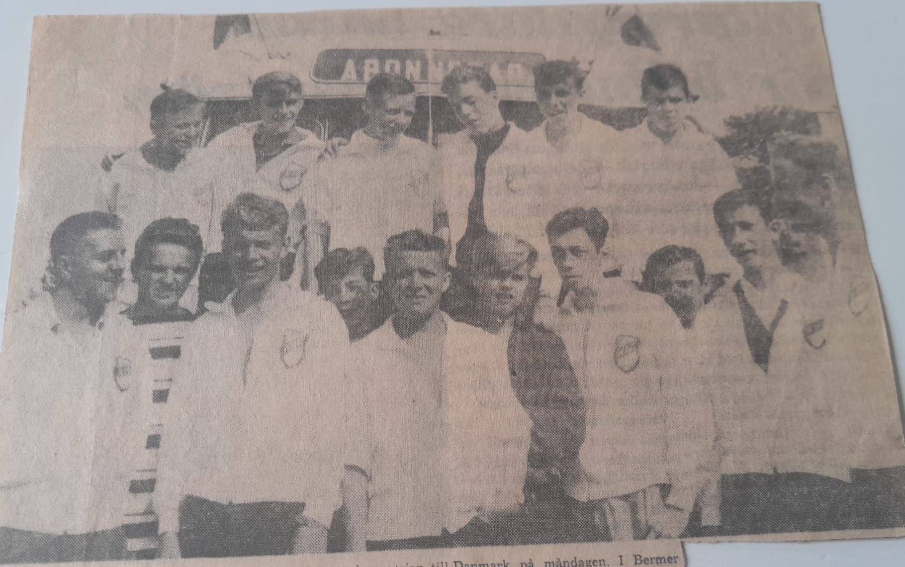 Original tidningsbild av ett ungdomslag samlat framför en buss