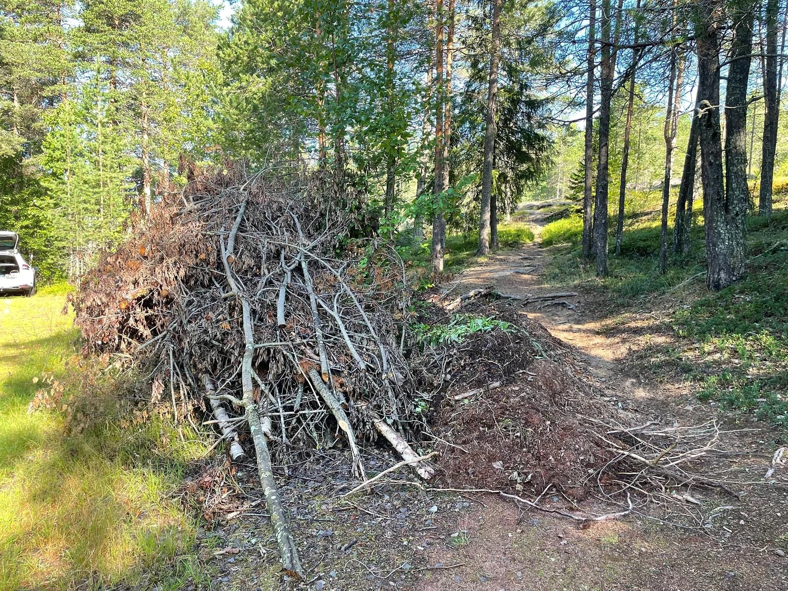 Stor hög med avverkade grenar efter röjning runt grusbanan